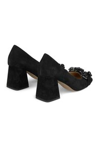 Scarpe in suede nere con tacco a blocco, punta tonda e decorazioni in cristallo nero sulla parte anteriore. La suola è leggermente testurizzata.