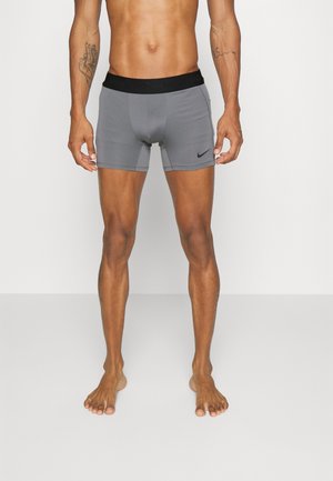 Mannen sportieve grijze shorts met een zwarte elastische tailleband, voorzien van een subtiele logo. Materiaal lijkt soepel en aansluitend.