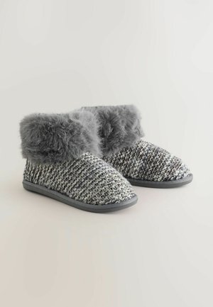 Gray knitted slippers with faux fur cuff, rounded toe, and rubber sole. Texture combines woven pattern with soft fur accents.