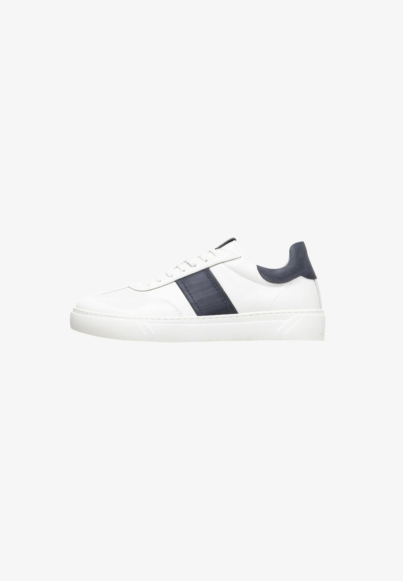 White leather sneaker featuring a navy blue textured accent stripe and heel, with a flat rubber sole and lace-up design.