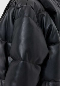 Giacca a vento nera in pelle con un design trapuntato, spalle arrotondate e una texture liscia. Dettagli con zip delineati.