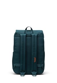 Sac à dos texturé en teal avec des sangles réglables, une poignée supérieure et un accent en cuir marron. Il présente une forme rectangulaire et un design épuré.