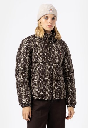 Nafukovacia bunda so vzorom hadích šupín v hnedých a béžových odtieňoch, s vysokým golierom a elastickými manžetami, doplnená o svetlobéžovú čiapku.