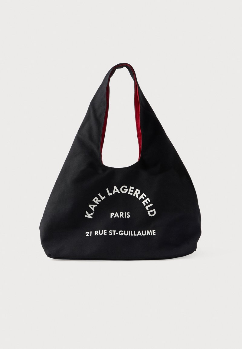 Sac cabas en tissu noir avec doublure intérieure rouge, avec texte blanc "Karl Lagerfeld Paris 21 Rue St-Guillaume" sur le devant.