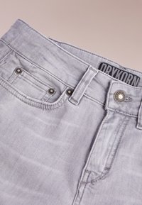 Jeans in denim grigio con chiusura frontale a bottoni, classico design a cinque tasche e etichetta del marchio "DRYKORN" sulla vita.