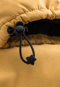 Tessuto giallo con una texture a coste, dotato di un cordoncino nero con un fermo a forma di stella, arricciato sul bordo di una giacca o cappuccio.
