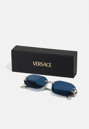 Versace sunglasses with dark blue lenses, octagonal shape, silver accents, and a black box featuring gold lettering.