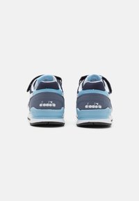 Sneaker azzurri e bianchi con tomaia in rete, colletto imbottito e cinturino regolabile. Presentano una suola nera texturizzata e il marchio sul tallone.