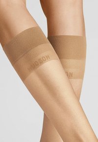 Beige Strumpfhalterstr�ümpfe mit einem strukturierten oberen Rand, der dezente Markenkennzeichnung aufweist. Transparente, glatte Oberfläche, die dafür entworfen ist, an den Oberschenkeln zu bleiben.