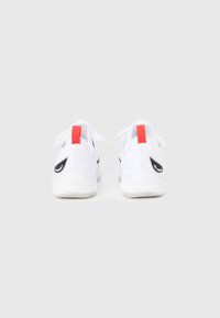 Λευκά αθλητικά παπούτσια με λείο υφασμάτινο πάνω μέρος, μαύρες λεπτομέρειες σχήματος swoosh, κόκκινα ταμπελάκια στη φτέρνα και λευκές λαστιχένιες σόλες. Διαθέτουν κορδόνια και μαξιλαρωμένα περιλαίμια.