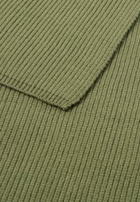 Tissu côtelé vert olive avec une texture douce, caractérisé par des lignes verticales et un bord replié, mettant en valeur son épaisseur et la qualité de son matériau.