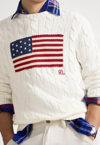 Camisola branca de malha com padrão de cabo, apresentando um desenho da bandeira americana em vermelho e azul na frente, com bordado vermelho "RL" e punhos de camisa aos quadrados.