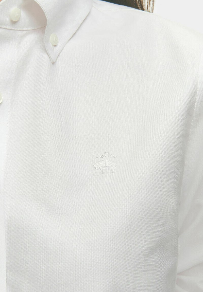 Biała koszula z guzikiem, wykonana z gładkiego materiału, z dyskretnym haftowanym logo na piersi i klasycznym wzornictwem kołnierzyka.