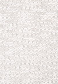 Gros plan d'un tissu tricoté blanc et doux avec un motif subtil et répétitif de mailles verticales et horizontales créant une texture.