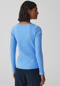 Lichtblauw geribd top met lange mouwen, een vierkante halslijn, een aansluitend ontwerp en een zachte textuur. Het kledingstuk heeft een slank silhouet en minimale details.