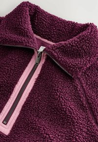 Fleece-pullovers i mørkeblå med høj krave, halv lynlås med sølvhardware, med pink kant og tekstureret, fluffy stof.