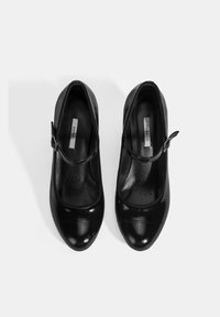 Zwarte lakleren Mary Jane-schoenen met een ronde neus, textuur op het oppervlak, enkelbandje en gewatteerde zool met perforaties.