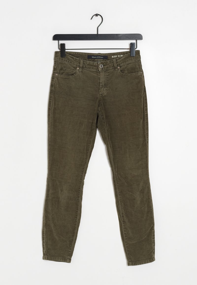 Pantalon en velours côtelé vert olive coupe ajustée suspendu à un cintre noir sur fond blanc.