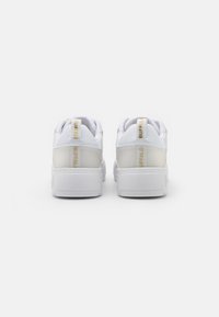 Vita sneakers med en slät syntetisk ovandel, rundad form, vadderad krage och en transparent hälaccent. Har "BUFFALO"-logotyp i guld.