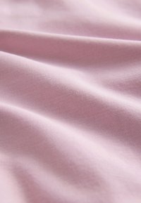 Mehak roza tkanina z drobno teksturirano tkanino in nežnimi gubami, ki ustvarjajo subtilne sence.