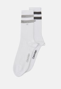 Calcetines de algodón blanco con textura acanalada, que presentan rayas grises y negras. Incluyen la marca Calvin Klein en gris y negro en los laterales.