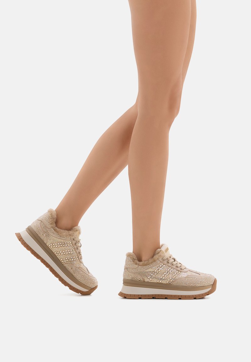 Sneaker beige con fodera in pelliccia, design intricato con perline, tomaia texturizzata e suola intermedia spessa bianca con suola in gomma.