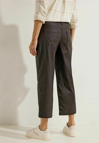 Zwarte cropped broeken met een soepele textuur, voorzien van twee achterzakken en een aansluitende tailleband, in combinatie met witte sneakers.