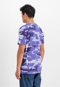 Ljubičasta kamuflaža majica s kratkimi rokavi, ki prikazuje različne odtenke vijolične in bele vzorce. Mehak material z udobnim krojem.