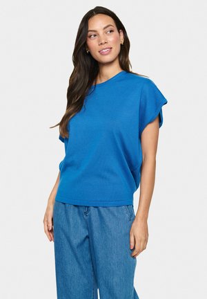 Top azzurro a maniche corte con vestibilità morbida, scollatura rotonda, tessuto testurizzato e lunghezza leggermente accorciata, abbinato a jeans blu chiaro a gamba larga.