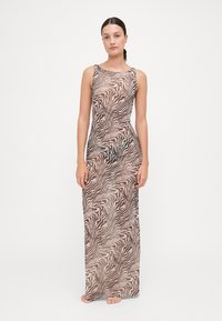 Abito lungo in tessuto leggero, caratterizzato da una stampa a strisce zebrate ondulate in beige e nero, design senza maniche e silhouette aderente.