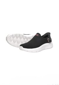 Zapatillas negras de slip-on con una parte superior texturizada, suela blanca y acentos florales en el talón. Ligeras y diseñadas para la comodidad.