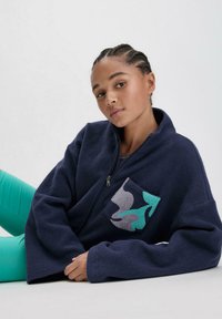 Marineblaue Fleecejacke mit einem Frontreißverschluss, ausgestattet mit einem strukturierten Taschendesign in Grau und Türkis. Bequeme Passform mit weiten Ärmeln.