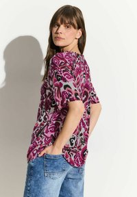 Top corto a maniche corte di taglio morbido in rosa e grigio con un audace motivo floreale; tessuto leggero, scollatura rotonda e orlo leggermente curvo.