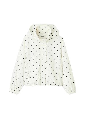 Veste blanche à capuche avec des pois noirs, fermeture éclair à l'avant, poignets élastiques et deux poches latérales.