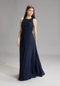 Marineblaues Maxikleid mit einem Spitzenoberteil und einem gewellten Ausschnitt; fließender Rock aus leichtem Stoff; bodenlanges Design.