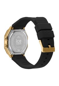 Montre octogonale avec un boîtier en acier inoxydable argenté, des accents dorés, et un bracelet en silicone noir avec une surface texturée.