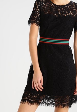 Schwarzes Spitzenkleid mit kurzen Ärmeln, einem gewellten Saum und einem mehrfarbigen gestreiften Gürtel. Die Textur ist detailliert und filigran.