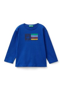 Niebieska, bawełniana koszulka z długim rękawem z graficznym nadrukiem, na którym znajdują się poziome paski oraz emblemat. Okrągły dekolt i luźny krój.