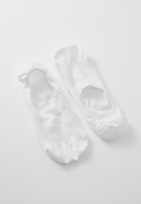 Calcetines blancos hasta el tobillo con una textura suave, que cuentan con aberturas elásticas y un diseño sin costuras, dispuestos de forma plana sobre un fondo claro.