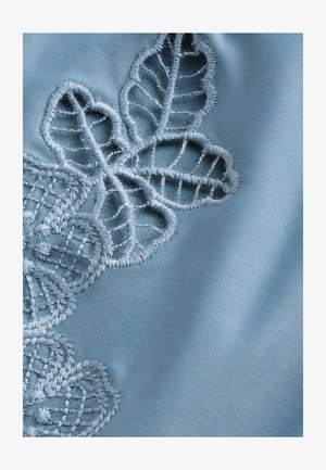 Jasnoniebieska tkanina z misternie wyhaftowanym wzorem kwiatowym, z motywami liści i szczegółowymi wzorami kratkowymi w kontrastowym kolorze nici.