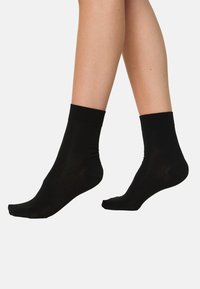 Sorte ankelstrømper med en glat tekstur, elastisk manchet og minimalistisk design. Fremstillet af et let materiale, velegnet til hverdagsbrug.