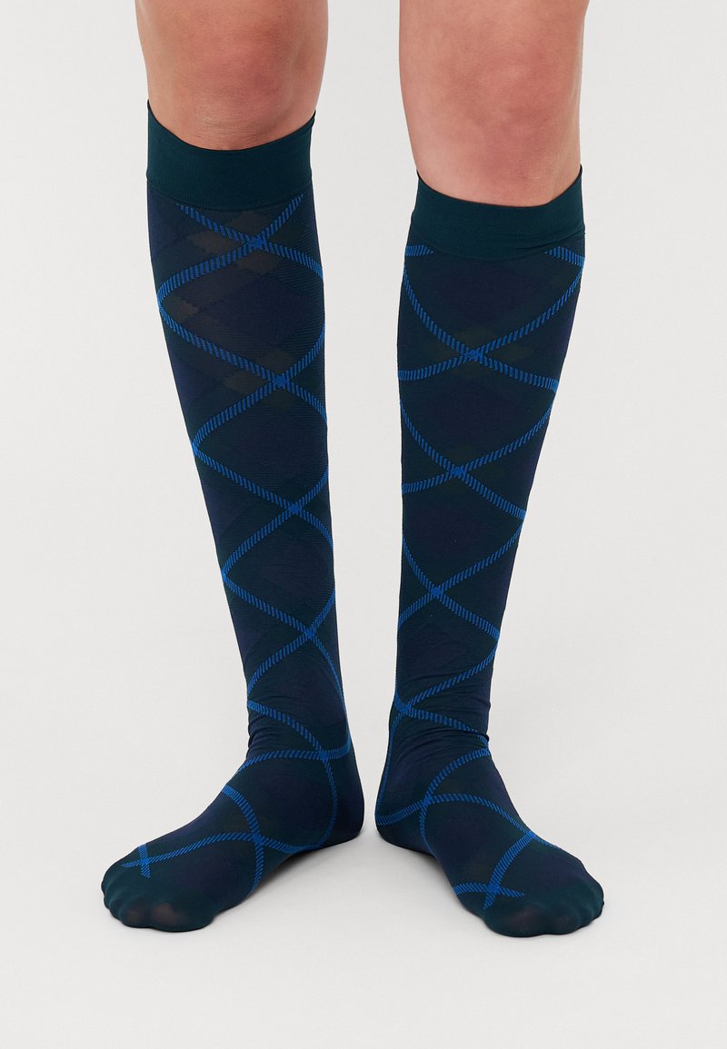 Calcetas hasta la rodilla en azul marino con un patrón de diamantes en líneas azules. Textura suave con un puño sólido oscuro en la parte superior.