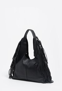 Czarna skórzana torba o zaokrąglonym kształcie, z długimi frędzlami po bokach i dużym, otwartym wnętrzem. Gładka faktura.