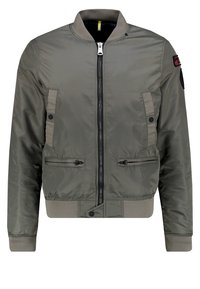 Olivově zelená bomber bunda s předním zipem, bočními zipovými kapsami a elastickými manžetami. Má žebrovaný límec a kontrastní tkaninové akcenty.