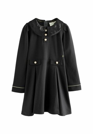 Schwarzes Kleid mit langen Ärmeln, rundem Kragen, vorderen Knöpfen, zwei Taschen mit perlenartigen Akzenten und dezentem goldenen Besatz an den Manschetten.