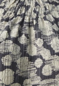 Mekko, jossa on puffi-hihat, on valmistettu tekstuurikankaasta, jossa on meriväri ja kerma-vaahto abstrakti kuvio, johon on ripoteltu pyöreitä muotoja.