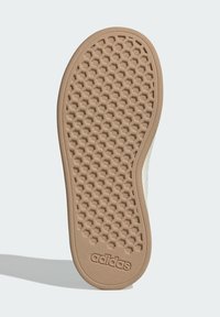 Gumová podrážka boty s hexagonálním vzorem běhounu, béžová barva s texturovaným povrchem; u paty je značka "adidas".