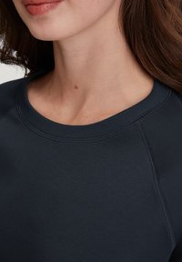 Marineblauwe sweatshirt met een geribde halslijn, zachte textuur en raglanmouwen. Naaddetails zijn zichtbaar langs de zijkanten en de halslijn.