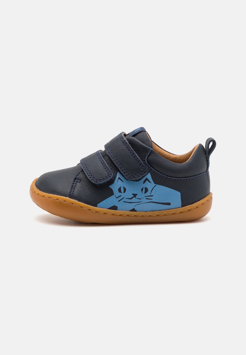 Blauer Lederschuh mit zwei Klettverschlüssen, auf der Seite mit einem Katzendesign und einer braunen Gummisohle. Glatte Textur, abgerundete Form.