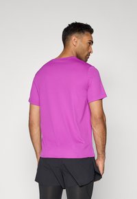 Tæt siddende T-shirt med korte ærmer i klar pink, lavet af glat stof. Har en rund halsudskæring og et enkelt design uden synlige logoer.